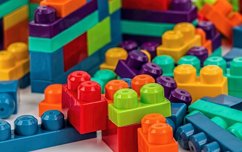 Pile of brightly colored interlocking plastic building blocks assembled into stacked structures